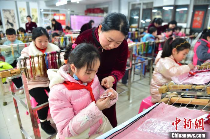 江西省級非遺豫章繡傳承人手把手指導(dǎo)小學(xué)生繡制2022年北京冬奧會吉祥物“冰墩墩”形象。　喻云亮 攝