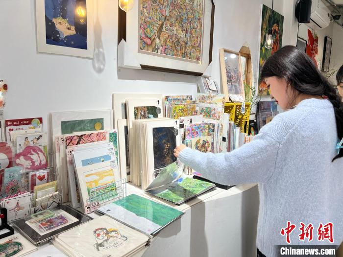 圖為藝術(shù)品商店內(nèi)，顧客挑選插畫作品?！＄婌?攝