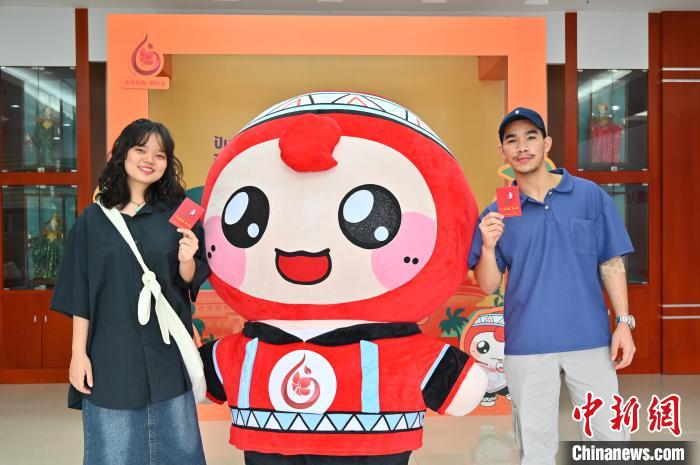 圖為泰國(guó)留學(xué)生手持獻(xiàn)血證與人偶合影。　俞靖 攝