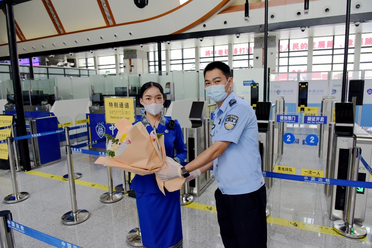 磨憨出入境邊防檢查站民警為中老鐵路第100萬名出入境旅客，D888次國際旅客列車?yán)蠐爰藙?wù)員森達(dá)拉·妮緹婭（Sengdala Nitiya），送上鮮花。黃遠(yuǎn)飛 攝
