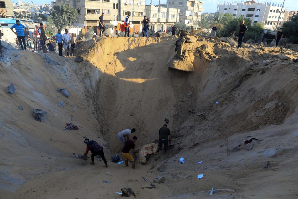 10月16日，在加沙地帶南部城市汗尤尼斯，人們在遭以色列襲擊后的建筑廢墟中救援傷者。 新華社發(fā)（亞西爾·庫迪 攝）
