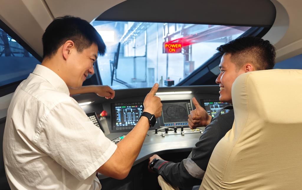 8月25日，在印度尼西亞萬隆的雅萬高鐵德卡魯爾動車所內，中國師傅穆振（左）在向印尼火車司機塞蒂亞萬講解動車組出庫前的上電作業(yè)。