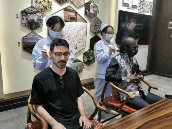 2023“一帶一路”媒體合作論壇聯(lián)合采訪團團員在九牛草展示館體驗艾灸。（本報記者 黃超攝）