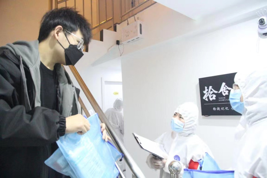 社區(qū)工作人員和志愿者身穿防護服上門送馬應龍大健康防疫包。徐帥攝