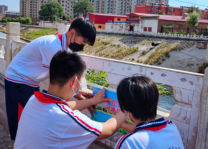 徐水小學(xué)學(xué)雷鋒志愿者在瀑河河邊張貼防溺水警示標(biāo)語。 徐水區(qū)委宣傳部供圖