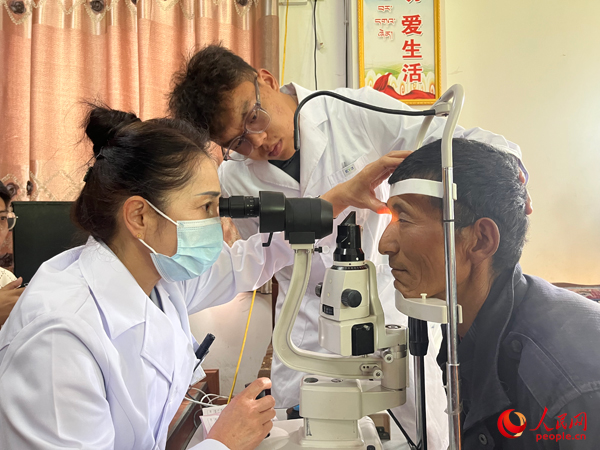 王紅英（左）和團(tuán)隊(duì)成員為達(dá)熱村村民檢查眼睛。人民網(wǎng)記者 杜燕飛攝
