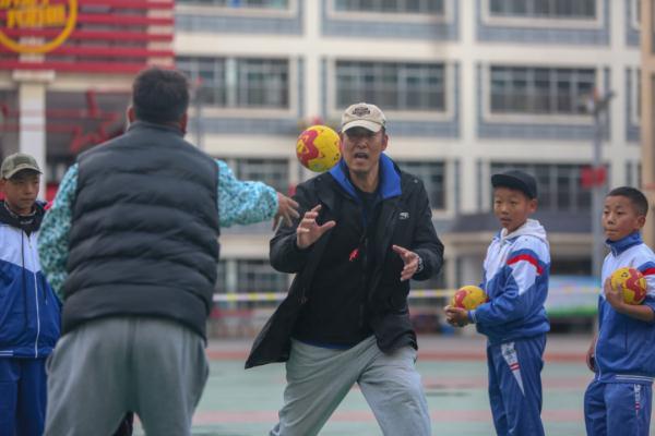 在高原上教孩子們打手球，“慢慢兒來(lái)，甭著急！”