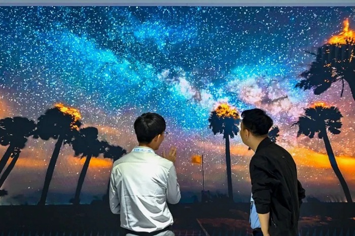 長春光博會希達電子展區(qū)，一位工作人員正在給一位觀眾講解。（長春新區(qū)供圖）