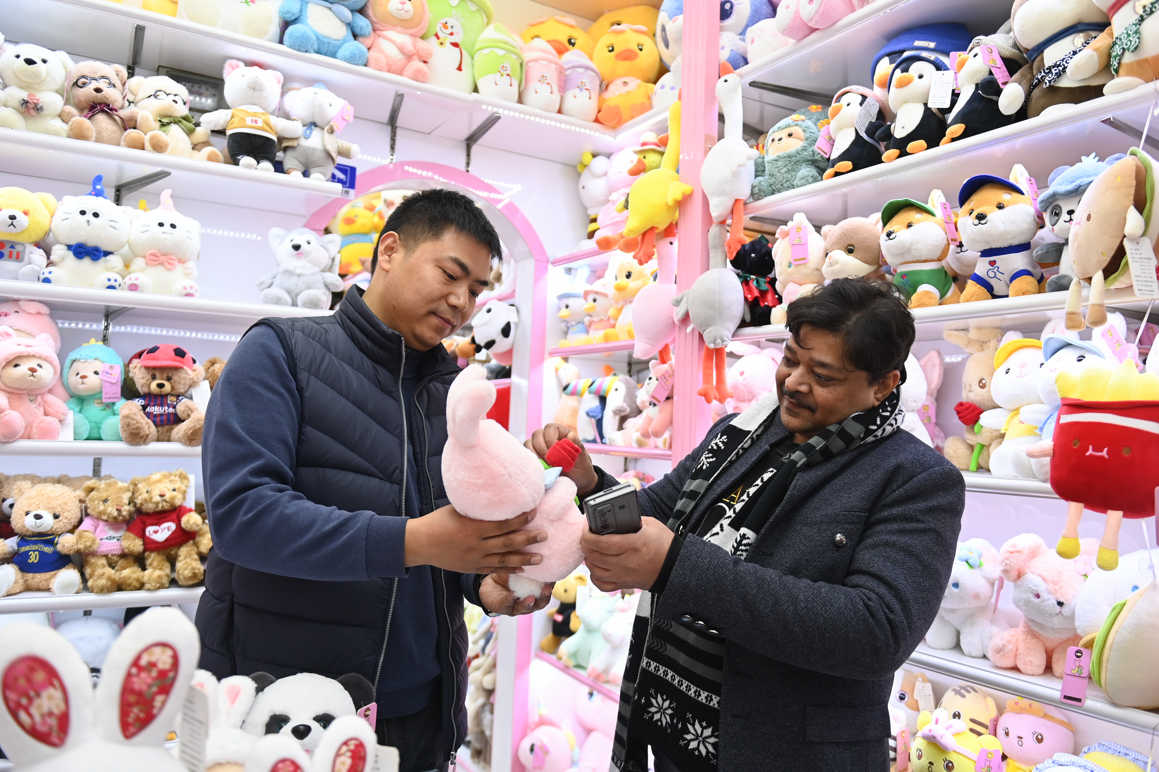 2023年2月2日，來自印度的客商（右）在義烏國際商貿(mào)城的一家玩具店鋪內(nèi)選購。