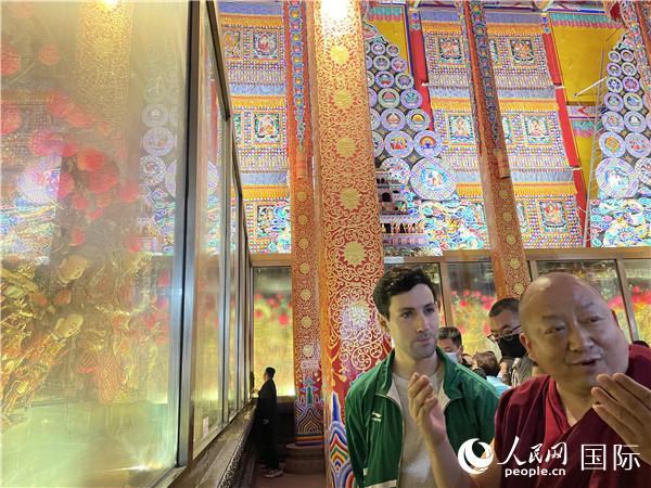 7月25日，省級非物質(zhì)文化遺產(chǎn)項目塔爾寺酥油花的代表性傳承人朋措堅參（右）在塔爾寺酥油花館講解酥油花的制作過程。人民網(wǎng) 謝瑩攝