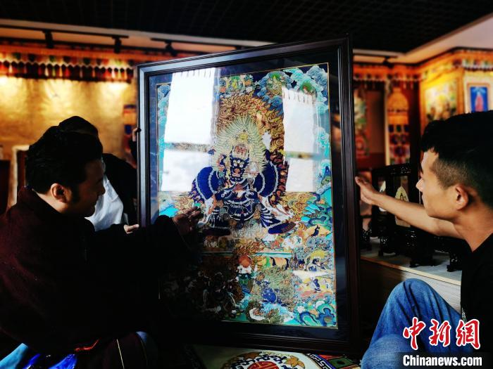 圖為久美尖措(左)與徒弟們展示唐卡作品。　張?zhí)砀?攝
