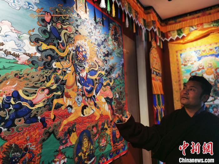 圖為久美尖措展示唐卡作品?！?zhí)砀?攝