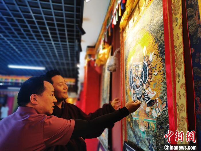 圖為久美尖措展示唐卡作品?！?zhí)砀?攝
