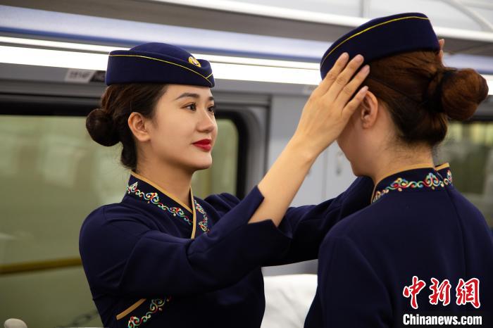 圖為青藏鐵路西格段“復(fù)興號(hào)”動(dòng)車組乘務(wù)員互相整理新制服?！±罾?攝