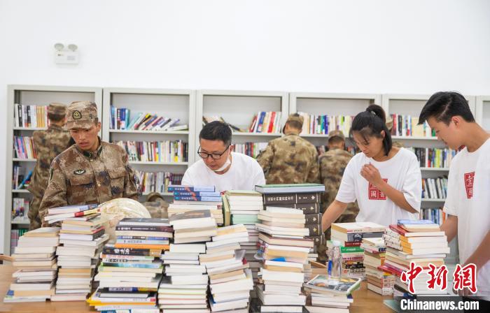 圖為志愿者們和邊防戰(zhàn)士整理圖書?！詵| 攝