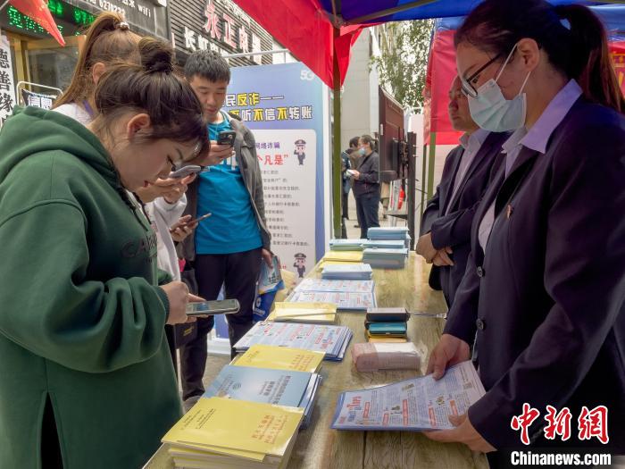 圖為工作人員正在向路過市民介紹國家反詐中心軟件的功能?！≈x牧 攝