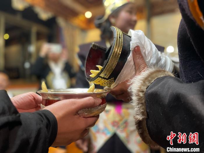圖為主人在碗中斟滿青稞酒?！∪轿木?攝
