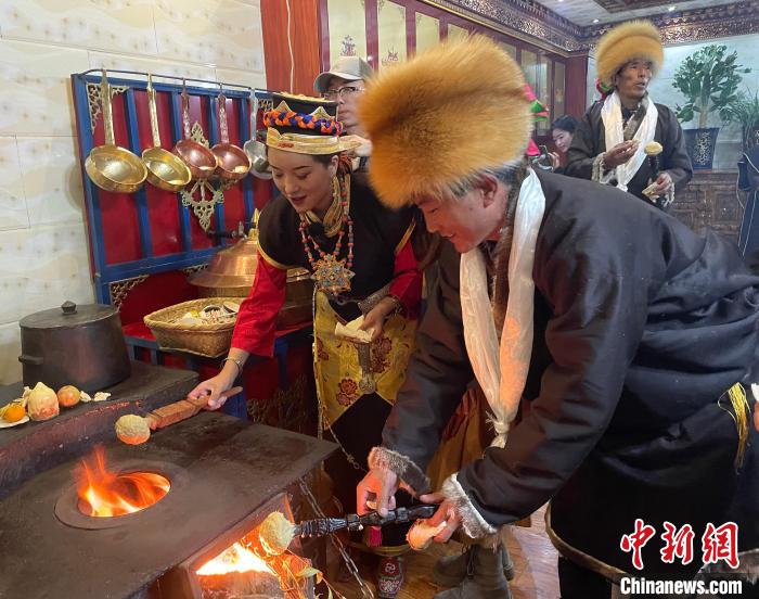 圖為人們在火上烤節(jié)日美食“結達”?！∪轿木?攝