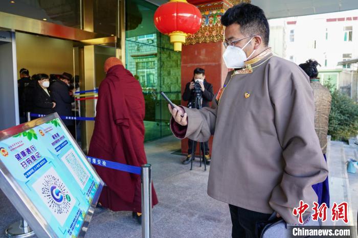 圖為政協(xié)委員掃場所碼進(jìn)入會場?！〗w波 攝