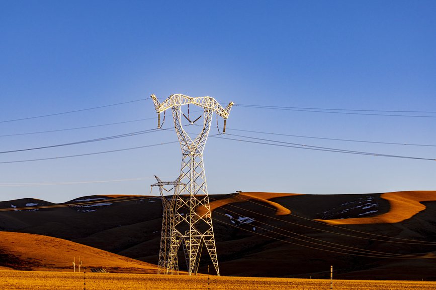 阿里地區(qū)的曠野上，電力鐵塔在夕陽(yáng)下熠熠生輝。