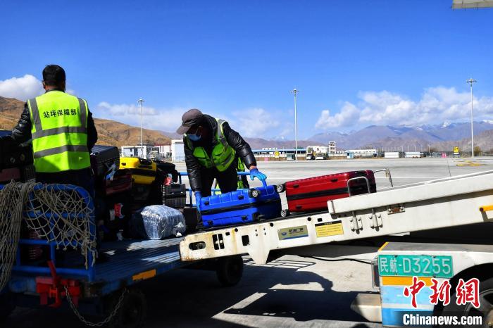 圖為機場工作人員傳送旅客行李箱?！≈芎?攝