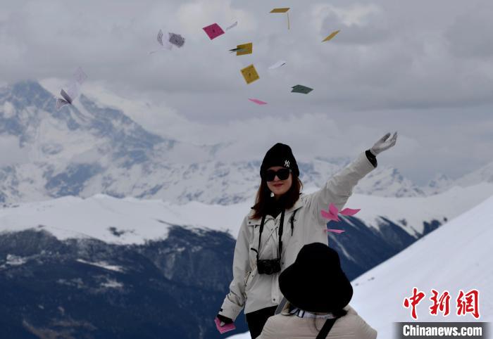 圖為5月14日，游客在西藏林芝色季拉山觀景臺拋灑“隆達(dá)”(風(fēng)馬旗，藏族民眾的一種祈福方式)?！±盍?攝